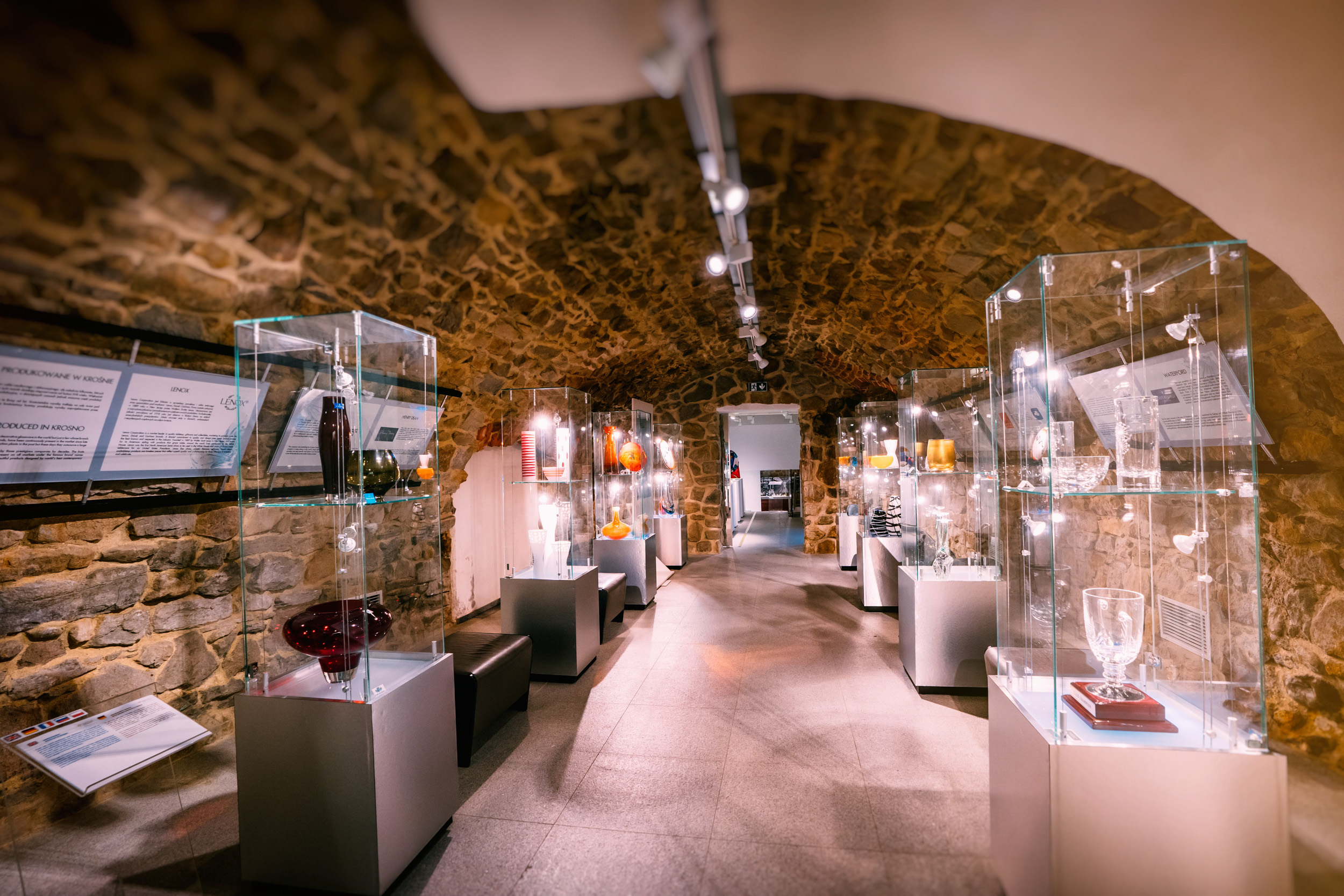 Wnętrze Muzeum, widok na podświetlone gabloty z eksponatami  - wyrobami ze szkła